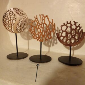 « Sculpture miniature en bois ajouré, formes organiques verticales évoquant une forêt stylisée ou des troncs entrelacés, montée sur une tige métallique noire avec socle rond »