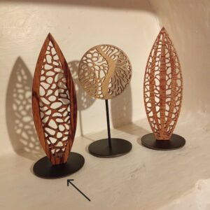 Trois sculptures de la collection Mini Forêt en bois ajouré sur socles noirs, dont une forme verticale élancée en bois de serpent à gauche, photographiées ensemble sur fond clair.