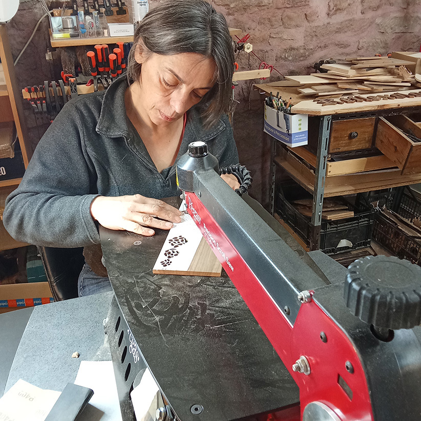 Corinne Bouloc en train de sculpter une pièce en dentelle de bois dans son atelier