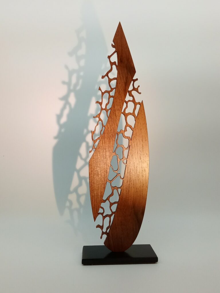 Sculpture en bois ajourée en dentelle de bois, pièce unique réalisée à la main, dont l’ombre se projette sur le mur selon l’éclairage