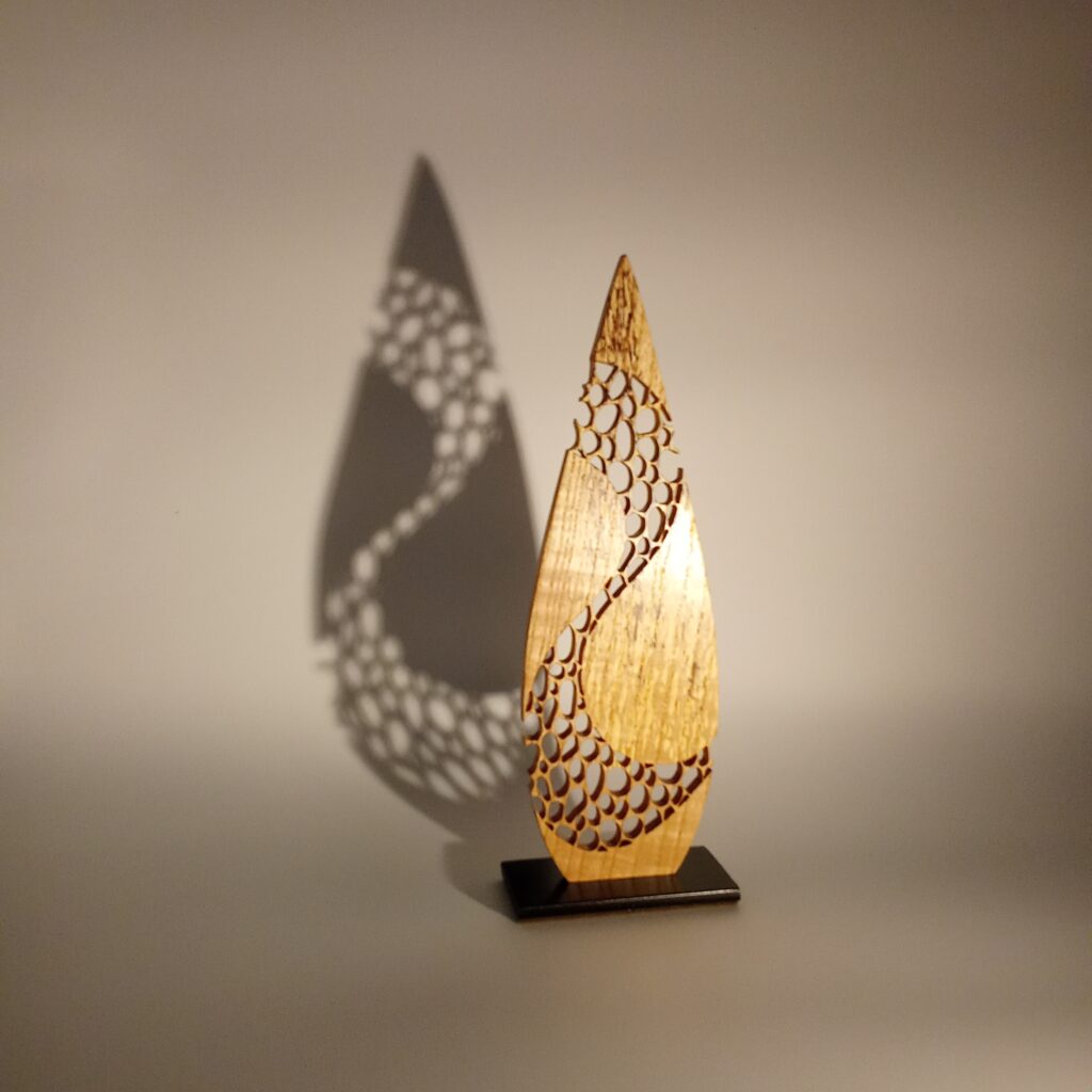 Sculpture sur bois ajourée laissant apparaître une ombre projetée, création artisanale de l’atelier Tutti Colori en Aveyron (Occitanie)