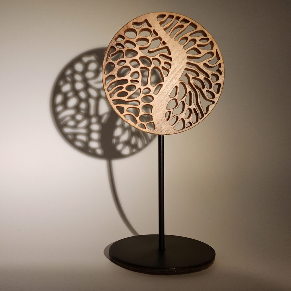 Mini Forêt 3, sculpture en bois ajouré avec ombre marquée sur fond chaud