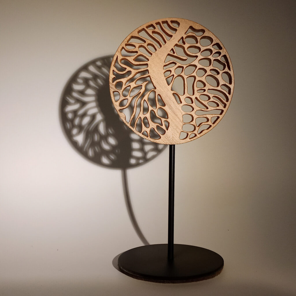 Mini Forêt 3, sculpture en bois ajouré projetant une ombre forte sur fond chaud