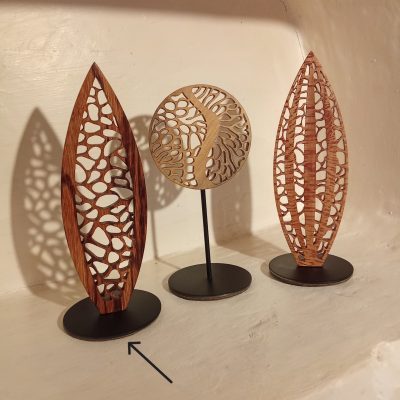 Trois sculptures de la collection Mini Forêt en bois ajouré sur socles noirs, dont une forme verticale élancée en bois de serpent à gauche, photographiées ensemble sur fond clair.